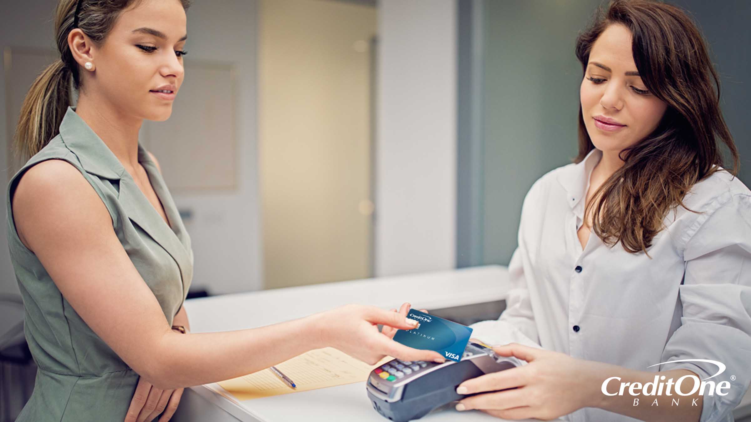 A woman pays her medical bill with a credit card at the doctor’s office, perhaps after considering the benefits of doing so.
